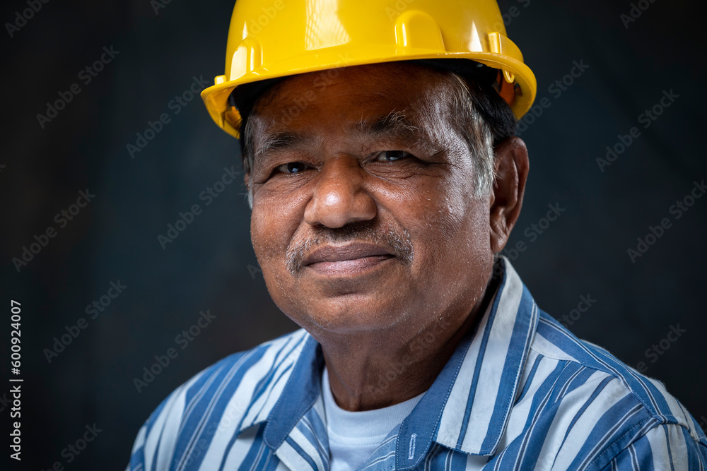 Portrait smiling of senior engineer wearing yellow helmet looking at camera on the dark background in studio. Portrait smiling of senior engineer wearing yellow helmet looking at camera on the dark background in studio.