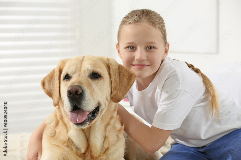 Cute child with her Labrador Retriever at home. Adorable pet