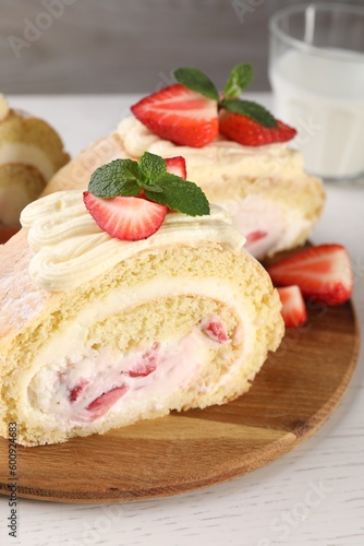 Delicious cake roll with strawberries and cream on wooden board, closeup