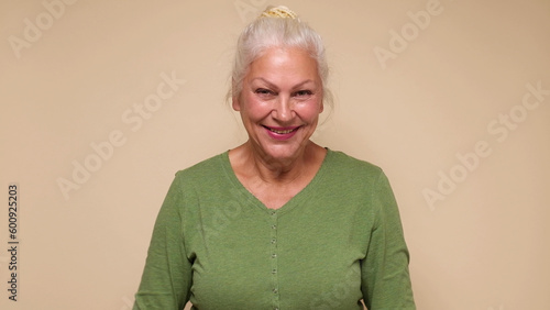 An elderly European woman in glasses confidently looks into the camera, smiling