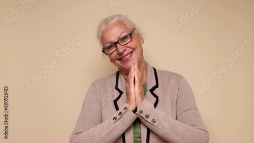 An elderly European woman is praying for help, holding her palms together. Do me a favor photo