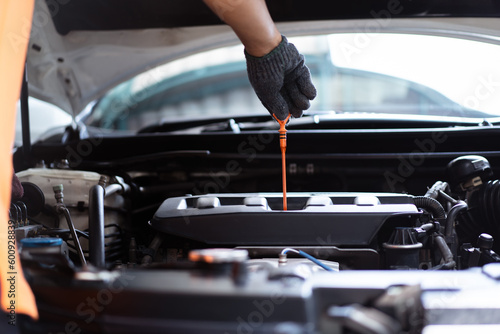 Senior Asian man checking or measuring a vehicle oil engine or engine lubricant level by using oil stick indicator.