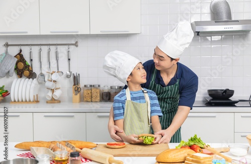 Little boy chef wearing white tall cook hat and apron.