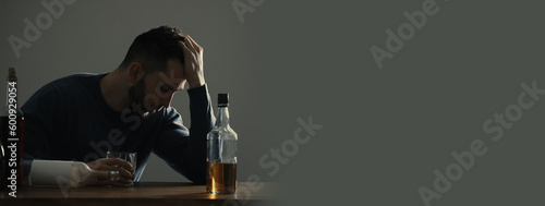 Suffering from hangover. Man with alcoholic drink at table against grey background, space for text. Banner design photo