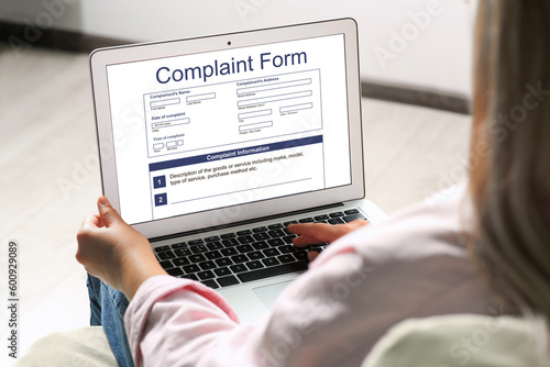 Fotografie Woman filling online complaint form via laptop indoors, closeup