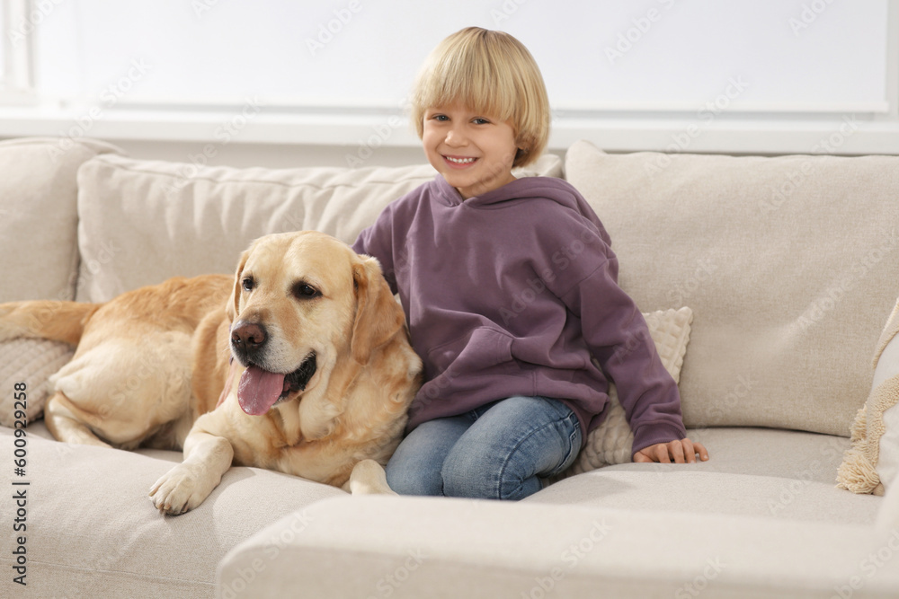Cute little child with Golden Retriever on sofa at home. Adorable pet Cute little child with Golden Retriever on sofa at home. Adorable pet