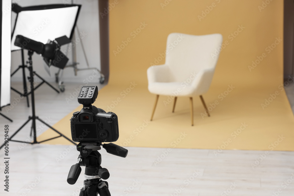 Camera on tripod, armchair and professional lighting equipment in modern photo studio, space for text Camera on tripod, armchair and professional lighting equipment in modern photo studio, space for text