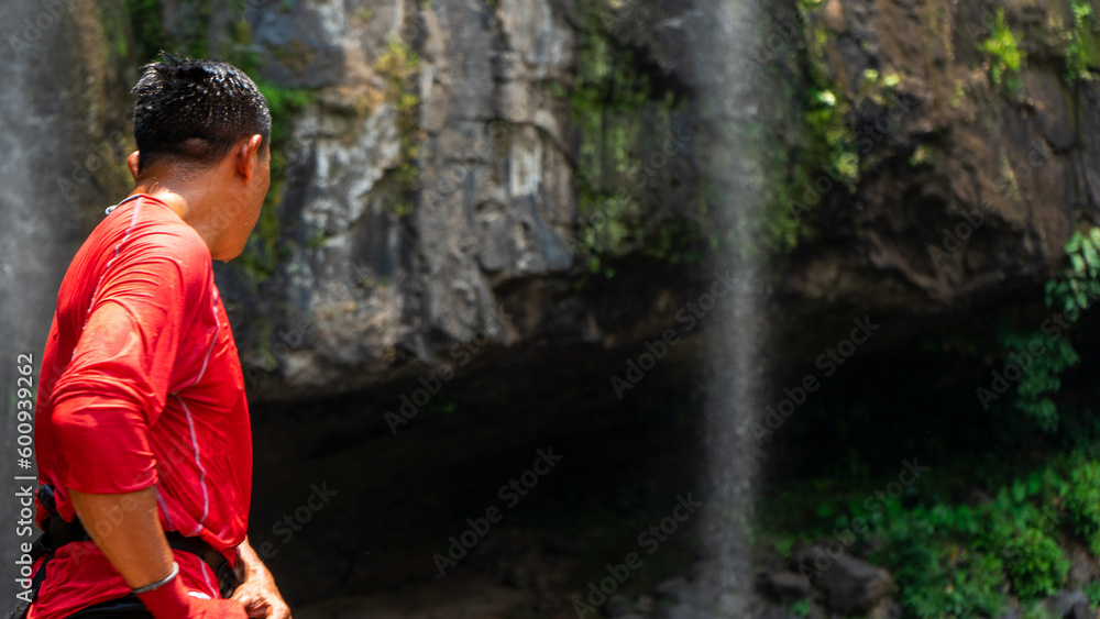 Unrecognizable man prepared to climb the rocky area of a waterfall in the mountainous area of Matagalpa, Nicaragua
