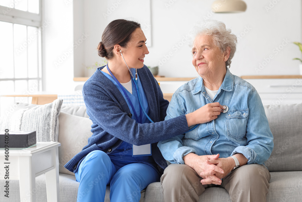 Young caregiver hearing senior woman with stethoscope at home Young caregiver hearing senior woman with stethoscope at home