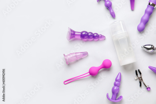 Bottle of lubricant and sex toys on white background