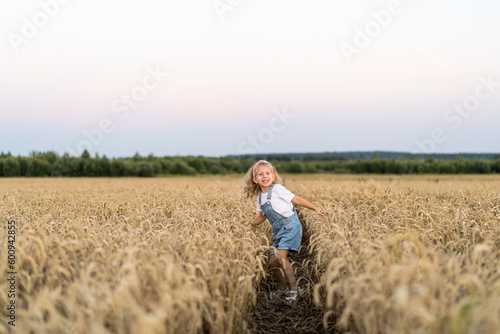 a little blonde curly girl running in a wheat field, the concept of human freedom