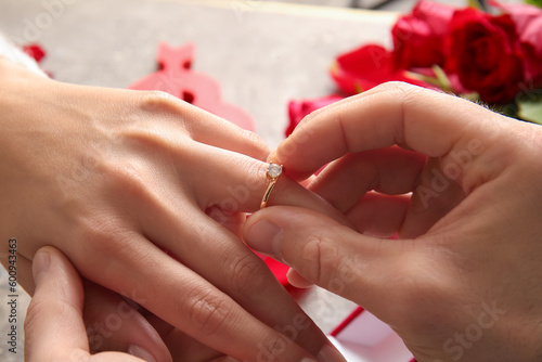 Man putting engagement ring on woman s finger  closeup