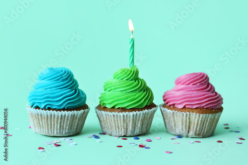 Tasty cupcakes with birthday candle on blue background
