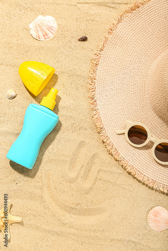 Creative composition with sunscreen cream, summer hat and sunglasses on sand