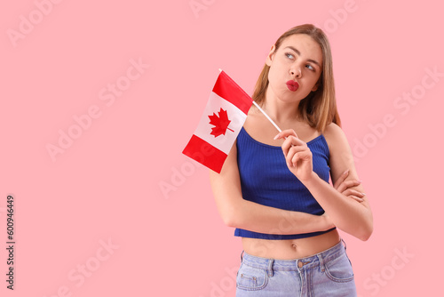 Thoughtful young woman with flag of Canada on pink background