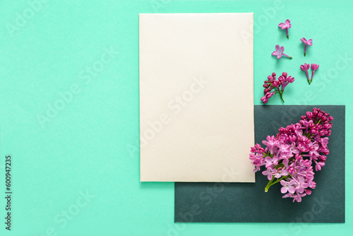 Composition with blank cards and lilac flowers on turquoise background