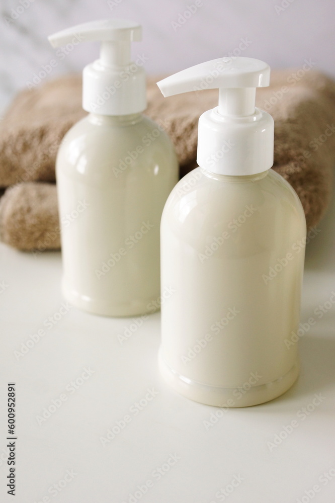 Natural cosmetic skincare bottles mockup and towel on white background with copy space. Product presentation. Beauty and body care products. Neutral beige colors. Natural cosmetic skincare bottles mockup and towel on white background with copy space. Product presentation. Beauty and body care products. Neutral beige colors.
