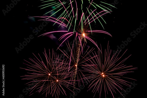 Bright beams of fireworks on black background of night sky. Festive fireworks.