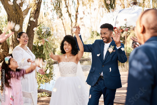 Wedding day, couple celebrate and confetti outdoor with happiness and hands up at marriage event. Celebration, happy people and African bride walking with flower bouquet at love commitment ceremony