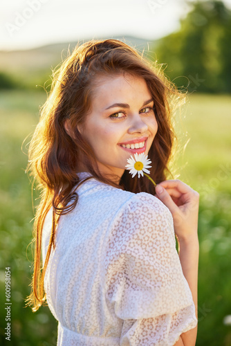Foto close portrait of a beautiful, laughing woman in a light dress holding a camomil