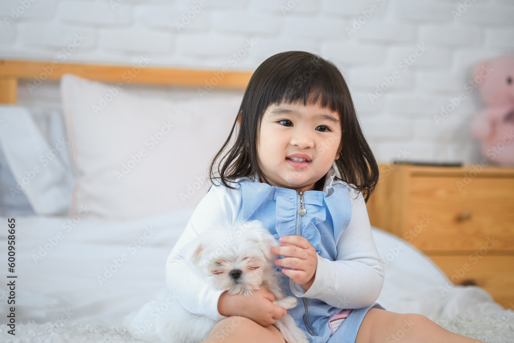 The dog seemed happy in the little girl's embrace with love and affection on bed in bedroom while looking to the camera. The dog seemed happy in the little girl's embrace with love and affection on bed in bedroom while looking to the camera.