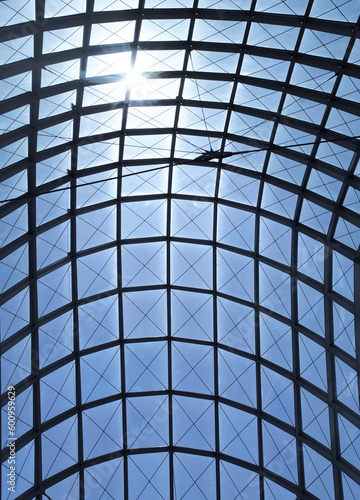 architecture detail pattern with the sun in a blue sky above a glass ceiling, vertical