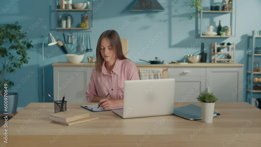 Smiling Young Woman University Student Takes Notes While Reading on Laptop.Smart Woman Studying from Home, Watching Webinars or Virtual Education Classes. Distance Learning and Work from Home Concept. Smiling Young Woman University Student Takes Notes While Reading on Laptop.Smart Woman Studying from Home, Watching Webinars or Virtual Education Classes. Distance Learning and Work from Home Concept.