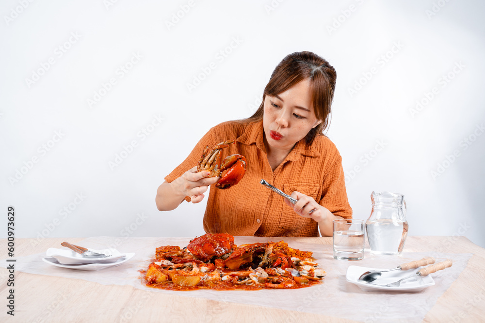 young asian woman enjoys eating seafood, crab with padang sauce (Indonesian : Kepiting Saus Padang) isolated on white background young asian woman enjoys eating seafood, crab with padang sauce (Indonesian : Kepiting Saus Padang) isolated on white background