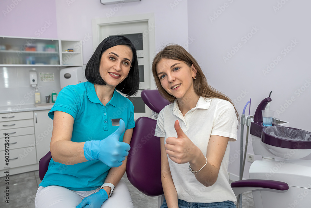 Fototapeta premium team of dentists and patient happily showing thumbs up.