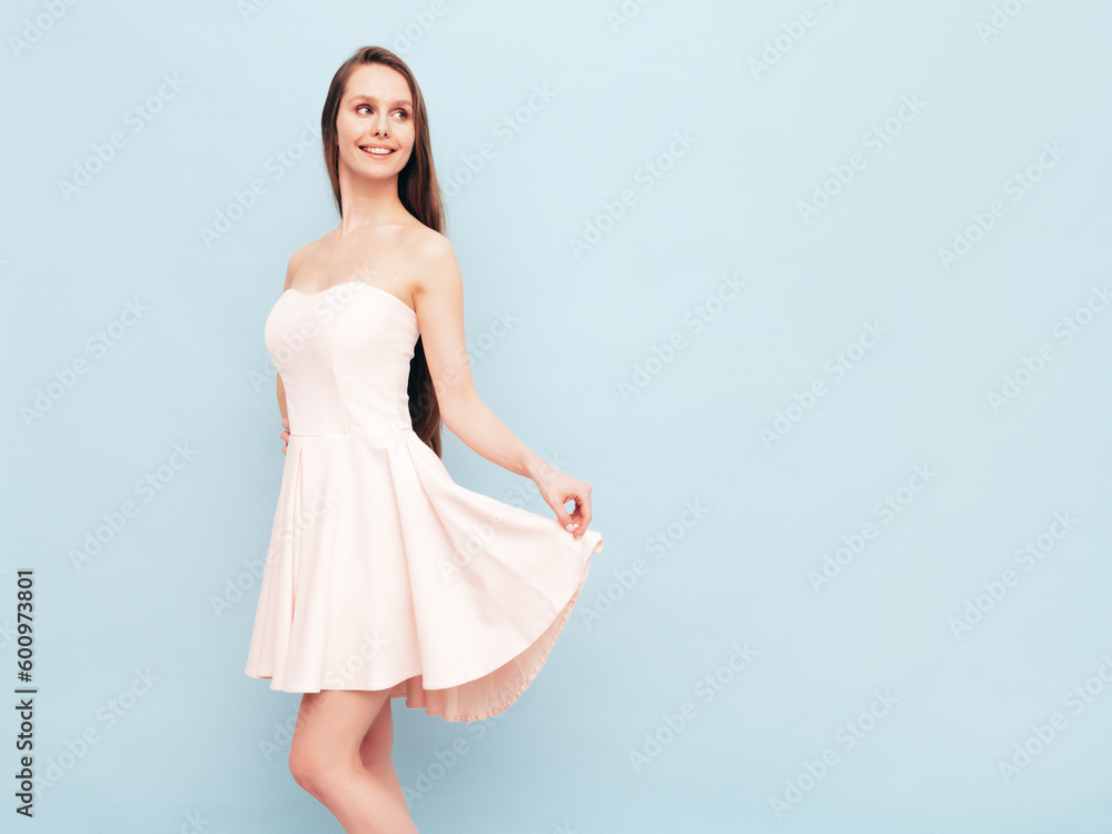 Portrait of young winsome woman in romantic attire pretty smiling on blue background. Slim female in pure pink dress posing in studio. Cheerful model. Isolated. Long hair Portrait of young winsome woman in romantic attire pretty smiling on blue background. Slim female in pure pink dress posing in studio. Cheerful model. Isolated. Long hair