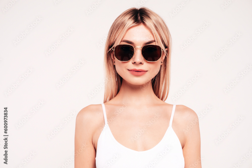 Young beautiful smiling blond female in trendy summer white top t-shirt clothes. Sexy carefree woman isolated on white background in studio. Positive model in sunglasses. Closeup Young beautiful smiling blond female in trendy summer white top t-shirt clothes. Sexy carefree woman isolated on white background in studio. Positive model in sunglasses. Closeup