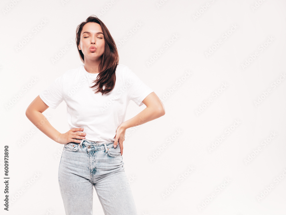 Fototapeta premium Young beautiful woman. Trendy carefree model in casual summer white T-shirt and blue jeans. Positive female isolated on white in studio. Cheerful and happy. Copy space, mockup. Makes duck face