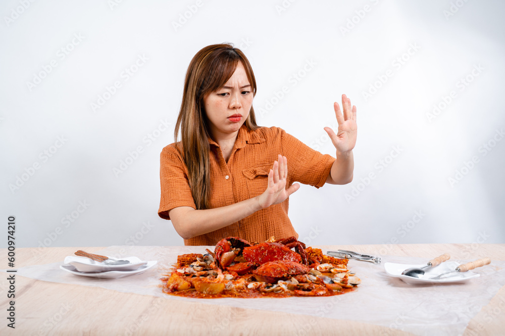 Young Asian woman say no to eating seafood, crab with padang sauce (Indonesian : Kepiting Saus Padang) isolated on white background Young Asian woman say no to eating seafood, crab with padang sauce (Indonesian : Kepiting Saus Padang) isolated on white background