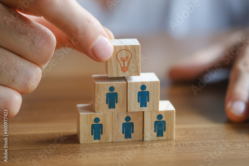 Man holding a wooden cube with light bulb on it. Teamwork and employment business concept