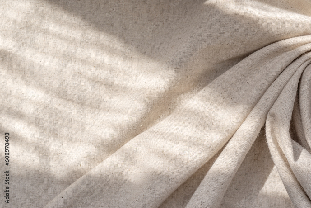 Aesthetic natural textile background with abstract sunlight shadow, neutral beige linen draped fabric, copy space - obrazy, fototapety, plakaty 
