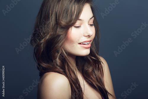 Beauty, cosmetic and young woman in a studio with a natural, face and makeup routine. Self care, beautiful and young female model with cosmetics, dermatology or skincare treatment by blue background.