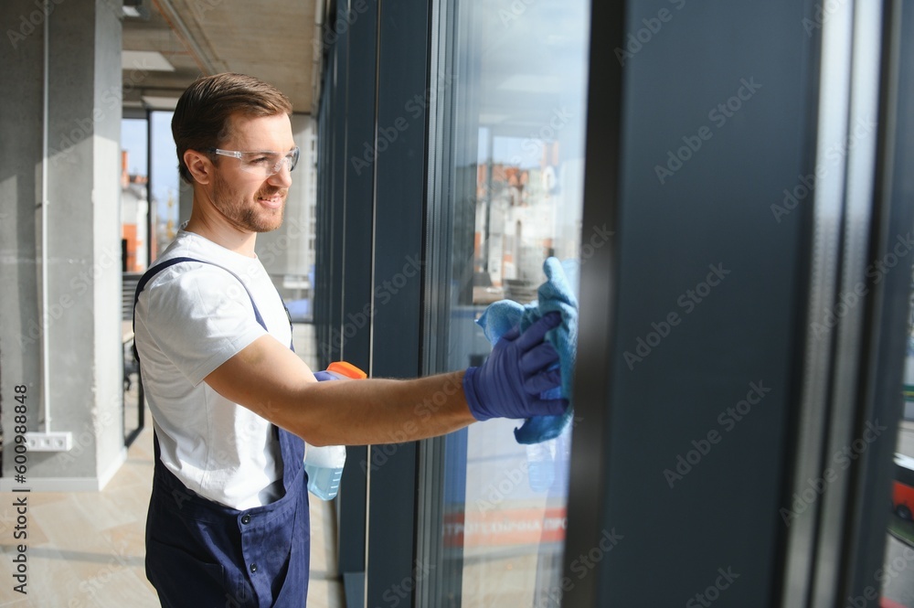 An employee of a professional cleaning service washes the glass of the windows of the building. Showcase cleaning for shops and businesses. An employee of a professional cleaning service washes the glass of the windows of the building. Showcase cleaning for shops and businesses.