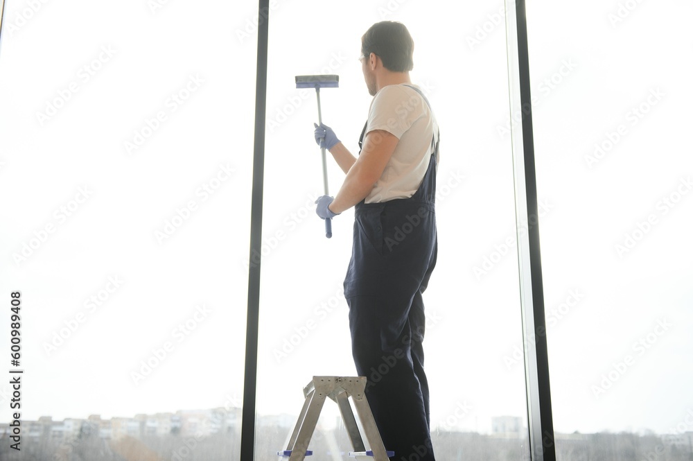 Male worker washing window glass