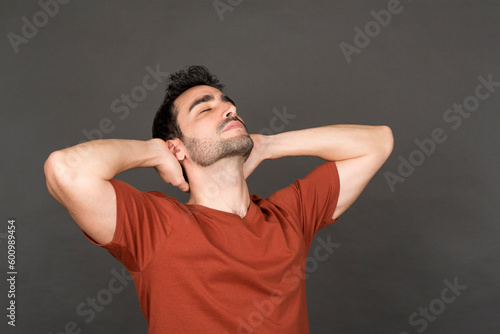 Relaxed young man with hands behind head in studio portrait. photo