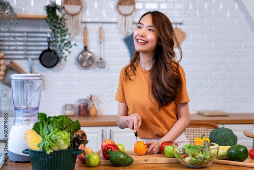 Beautiful young woman happy portrait cooking fresh organic clean food fruit at home modern kitchen