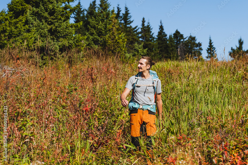 A tourist happily walks through the forest with a backpack, a countryside landscape, trekking in nature, a backpack on his back. A tourist happily walks through the forest with a backpack, a countryside landscape, trekking in nature, a backpack on his back.