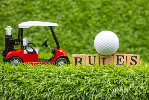 This photo shows a golf cart and golf ball on a green grass field with the word 