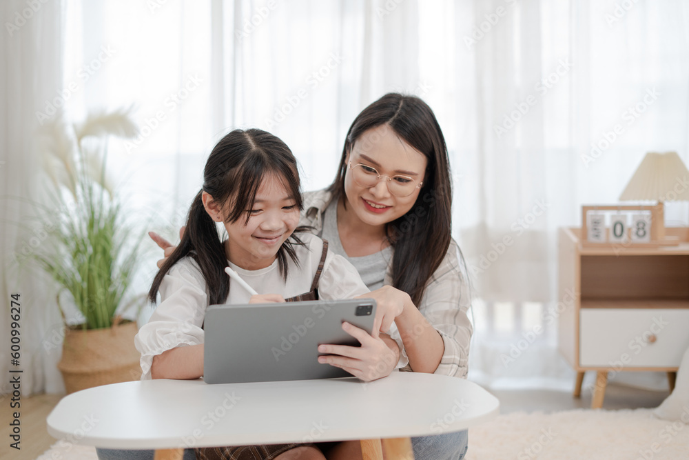 Asian family mother and daughter using the tablet in the home Asian family mother and daughter using the tablet in the home
