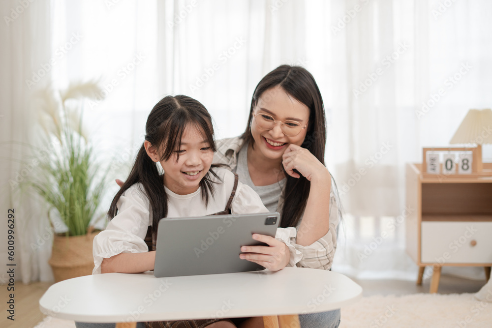 Asian family smiling of mother and daughter using the tablet in the home Asian family smiling of mother and daughter using the tablet in the home
