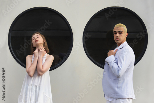Young girl and guy are sitting against background of black round windows of portholes