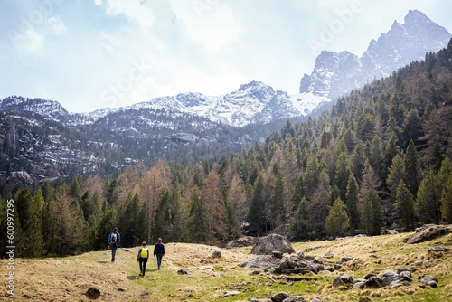 Three backpackers in a trekking in Aosta Valley, looking to the mountains, Italy