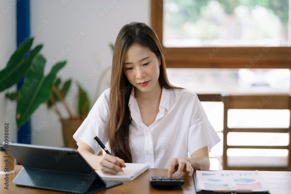 Businesswoman working with tablet and using a calculator to calculate the numbers of static in office. Finance accounting concept. Businesswoman working with tablet and using a calculator to calculate the numbers of static in office. Finance accounting concept.