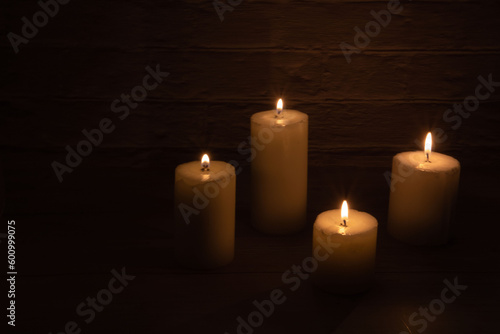 photo four burning candles of different sizes
