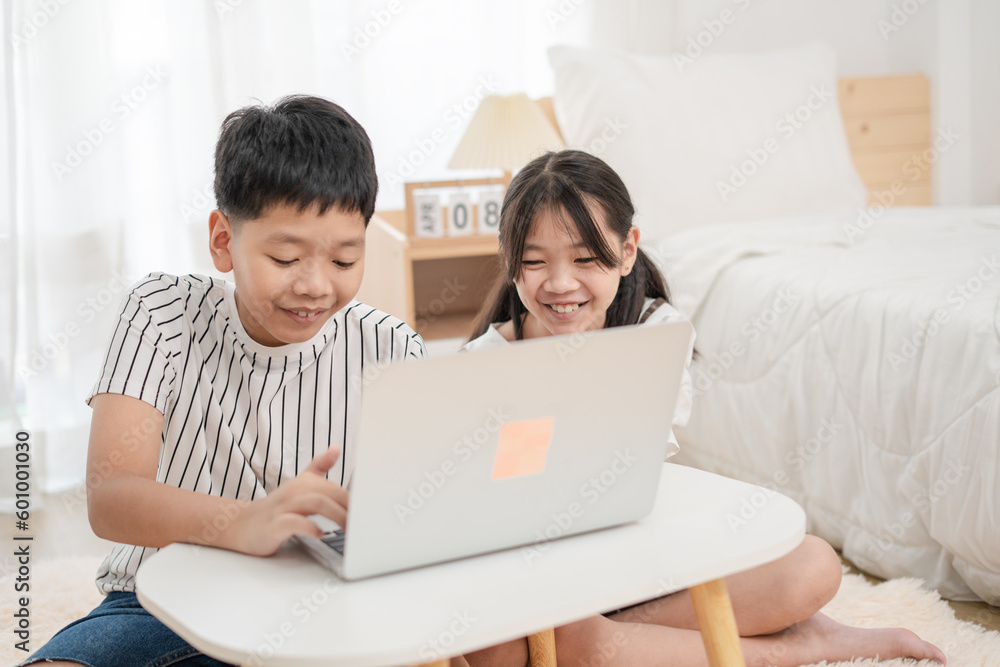 Asian brother and sister using laptop to learn at home