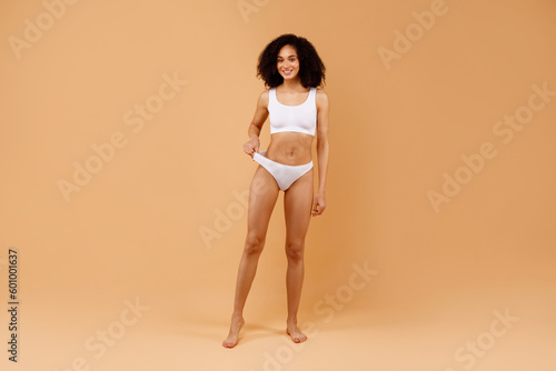 Full body length shot of fit black lady with slim body posing in underwear, woman with perfect sporty figure